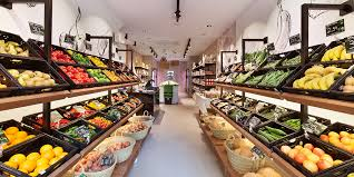 Interior de una tienda con estantes llenos de frutas y verduras frescas.